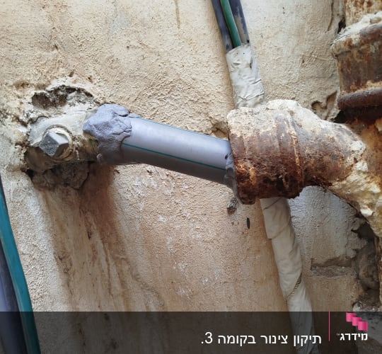 צינור מתכת מחובר לקיר עם חיבורים ותיקונים